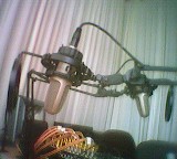 Zwei Studiomikrofone vor weißem Vorhang, verschränkt
