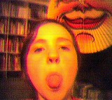 Mädchen streckt Zunge heraus, dahinter Bücherregal und Sonnenlampion